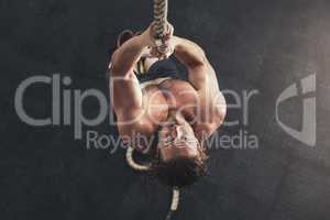 Beast mode comes naturally to me. Shot of a muscular young man climbing a rope in a gym.