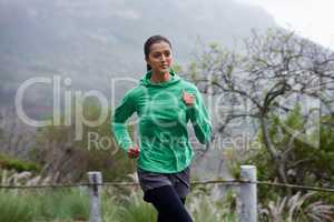 She progresses in her fitness everyday. A young woman sprinting along a mountain road on a crisp morning.