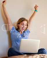 Thats a new high score. Shot of an happy young woman reacting to something exciting on her laptop at home.