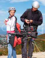 Getting ready for their tandem paragliding. Two paragliders checking their gear before jumping.