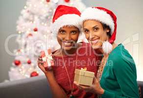 I wonder what she got me. Portrait of two excited friends holding up their Christmas gifts.