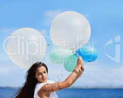 Sometimes you have to hold on tightly. Cropped shot of a gorgeous tattooed young woman holding balloons.