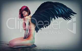 Dark Angel. Shot of a gorgeous woman with feathered wings in a fantasy-like setting.