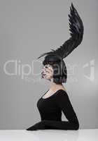 Soaring to new heights in fashion. Shot of a young woman in a wing-shaped headpiece sitting in a studio.