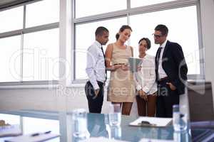 Defining the scope of their project. Shot of a group of businesspeople standing together looking at a digital tablet.