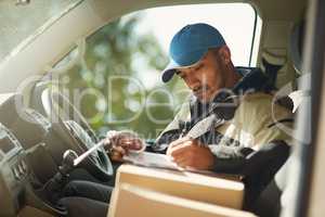 Updating his delivery status. Shot of a delivery man reading addresses while sitting in a delivery van.