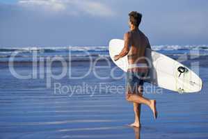 Chasing waves. A handsome young surfer at the beach craving a good wave.