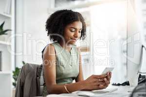 The smart way to navigate her work day. Shot of a young businesswoman using a mobile phone at her desk in a modern office.