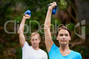 Exercise in fresh air. Shot of a man and woman using kettle bell weights in an outdoor exercise class.