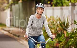 Just a gentle ride down the street. Portrait of a cheerful senior woman riding on a bicycle by herself outside in a suburb.