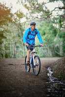 Keeping fit and enjoying nature. Shot of a male cyclist riding along a mountain bike trail.