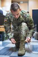 Brave is the man who wears combat boots. Shot of a young soldier tying his boot shoelaces in the dorms of a military academy.