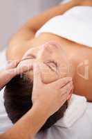 Retreating to a place of quiet relaxation. A young woman lying in a beauty spa receiving a relaxing head massage.