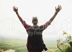 Life is meant to be lived. Rearview shot of a young man standing atop a mountain with his arms outstretched.