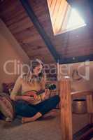 Lend me your ear and Ill sing you a song. Shot of a young woman playing the ukelele while relaxing in her bedroom at home.