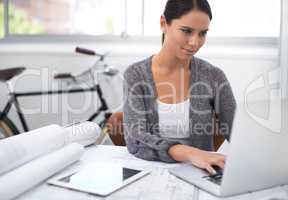 She eco-friendly and talented. Shot of a young female designer working at her laptop with a bicycle in the background.