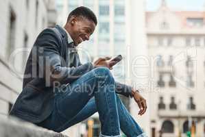 Welcome to Avenue Success. Shot of a young businessman sitting on the curb and using a smartphone against an urban background.