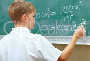 Hes a junior genius. Young schoolboy doing an equation on the blackboard at school.