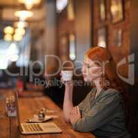 Relaxing with a fresh cup of coffee. Cropped shot of a young woman sitting with her laptop at a coffee shop.
