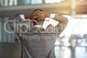 Business comes with its own unique pressure. Rearview shot of a businessman standing with his hands behind his head.