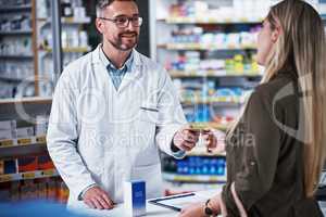 Yes, we do accept cards here. Shot of a young woman paying for merchandise with a credit card at a pharmacy.