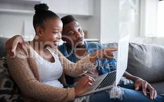 Check out this offer. Shot of a young couple using a laptop together on a sofa at home.