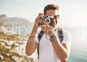 Say cheese. Cropped portrait of a handsome young man taking photographs while hiking in the mountains.