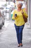 Nothing better than a cup of coffee in the morning. Shot of a mature woman on a sidewalk holding a takeaway beverage.