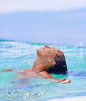 Having a tropical soak. Close up shot of a woman swimming in the swimming pool.