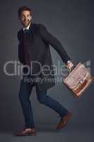 Looking good and good to go. Studio shot of a stylishly dressed young man on the go against a gray background.