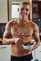 Nothing special but still delicious. Portrait of a cheerful young man wearing only his underwear while enjoying a bowl of strawberries in the kitchen at home.