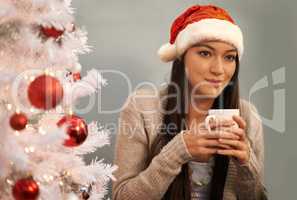 Drinking cocoa and thinking about Christmas. Cropped shot of an attractive young woman enjoying a hot drink on Christmas eve.