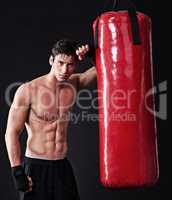This bag has had enough. Studio shot of a young mixed martial artist.