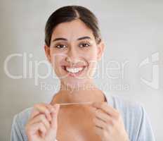 Regular flossing keeps my smile perfect. Portrait of an attractive young woman flossing her teeth.