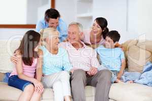 Enjoying grannys joke together. A loving family laughing on a lounge sofa together.