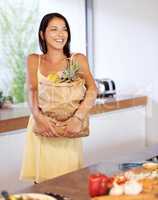 Creating a vegetarian feast. A young woman holding a bag of groceries in the kitchen.