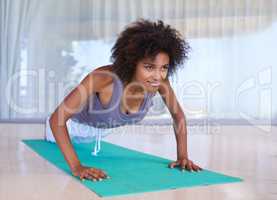 Working on her upper body. Shot of an attractive young woman doing push-ups on an exercise mat.