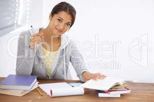 Hitting the books with a positive attitude. A pretty young university student studying for her finals in her dorm room.