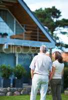 Finally we can afford our dream home. Rearview shot of a mature couple standing hand-in-hand in front of their home.