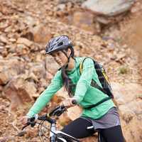 On a mission. An attractive young woman mountain biking in a scenic setting.