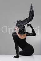 Feathered fashion. Shot of a young woman in a wing-shaped headpiece sitting in a studio.