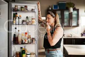 Hmm...what to make for dinner. Shot of a young woman searching inside a refrigerator at home.