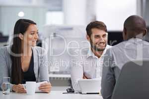 Thats his Friday smile. Three happy coworkers sitting down to have a meeting.