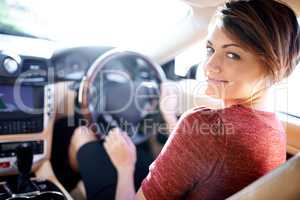 Im taking a roadtrip...care to join. Shot of a beautiful young woman driving a luxury car.