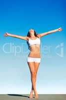 Feeling free. A carefree young woman standing against a blue sky with her arms outstretched.