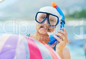 My inner child never passes up on a snorkelling opportunity. Shot of a mature woman wearing snorkel gear and holding an inflatable ball during a day on the beach.