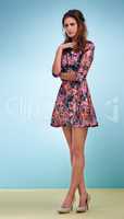 Flawless femininity. Full length shot of an attractive young woman wearing a floral dress against a blue background.