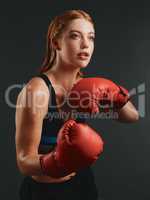 Its all about discipline. Studio shot of a sporty young woman wearing boxing gloves against a black background.