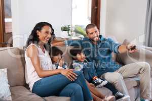 Its movie time for the whole family. Shot of a couple watching something on the television with their two young kids.