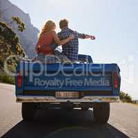 Define your own road in life. Shot of a young man pointing toward something while on a road trip with his girlfriend.